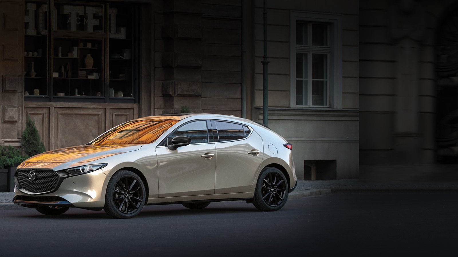 Une Mazda3 Sport platine garée dans la rue.