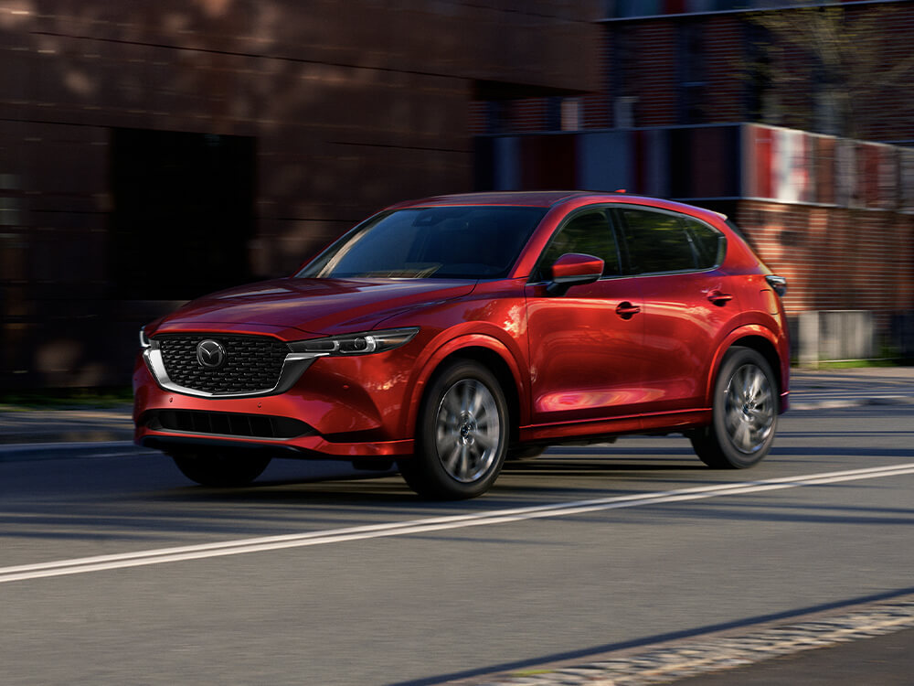 VUS Mazda rouge tournant à l’angle d’une rue pavée