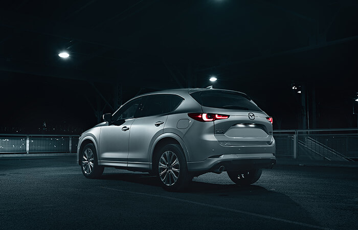 Vue arrière d’un CX-5 la nuit, à l’intérieur d’un stationnement; les feux arrière sont allumés. 