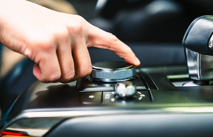 Driver adjusts controls on dashboard while driving.