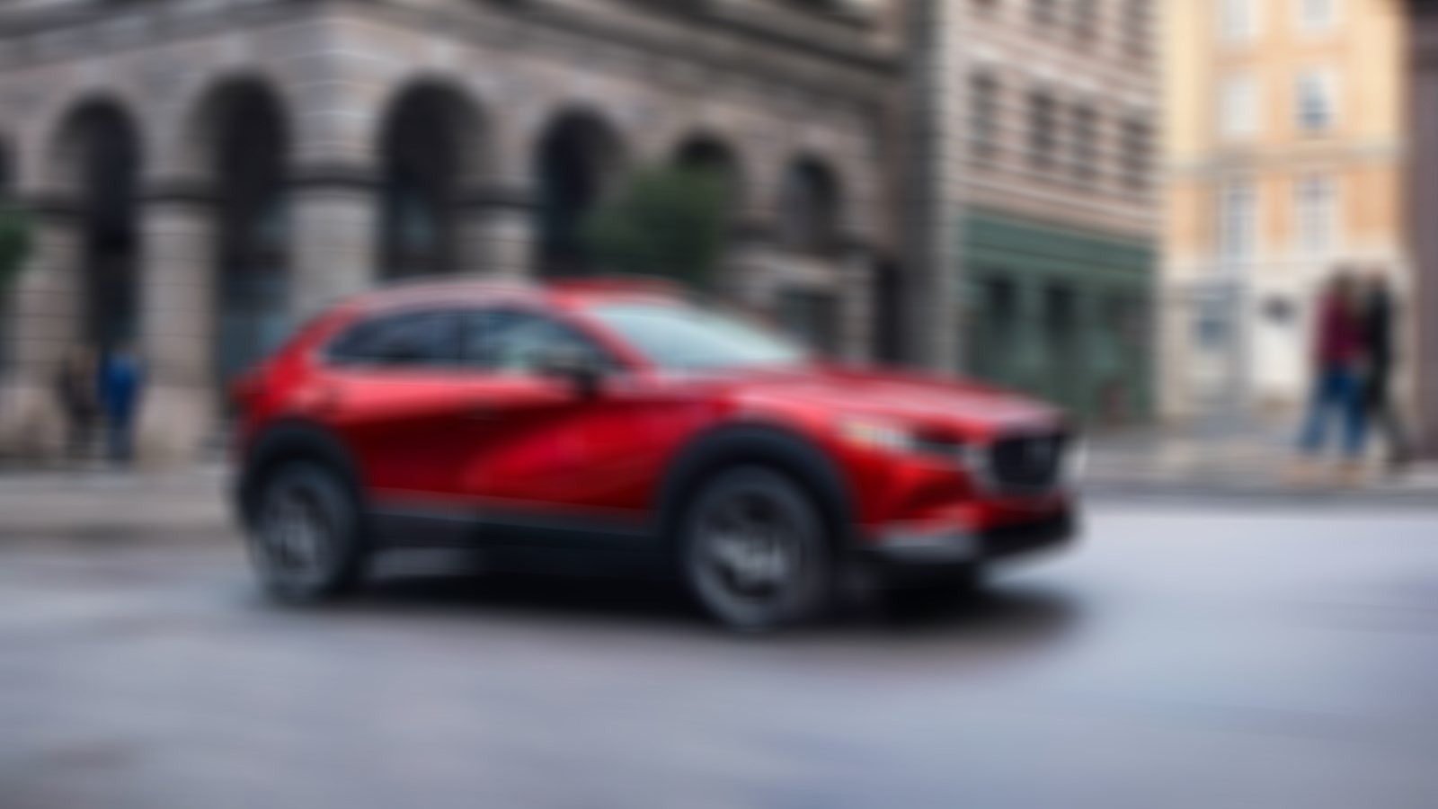 Soul Red Crystal Metallic CX-30 driving down main city street. 