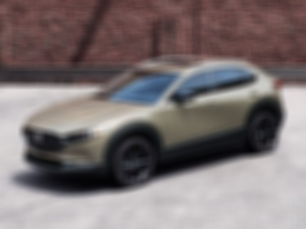 Zircon San Metallic CX-30 parked on road behind red brick building. 