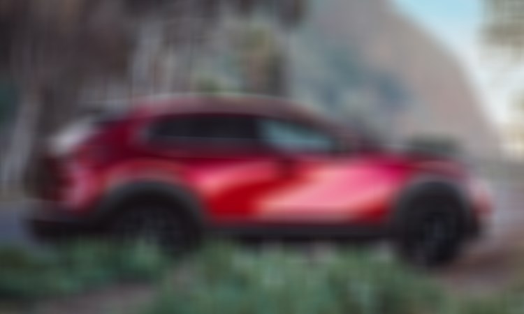 Passenger’s side profile of Soul Read Crystal Metallic CX-30 parked at the entrance of a coastal beach. 