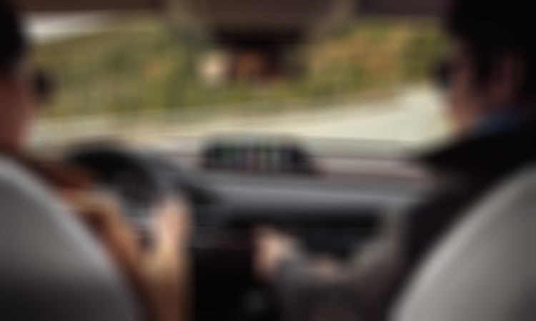 View from the CX-30's back seats peering past the driver and passenger, driving up escarpment road.