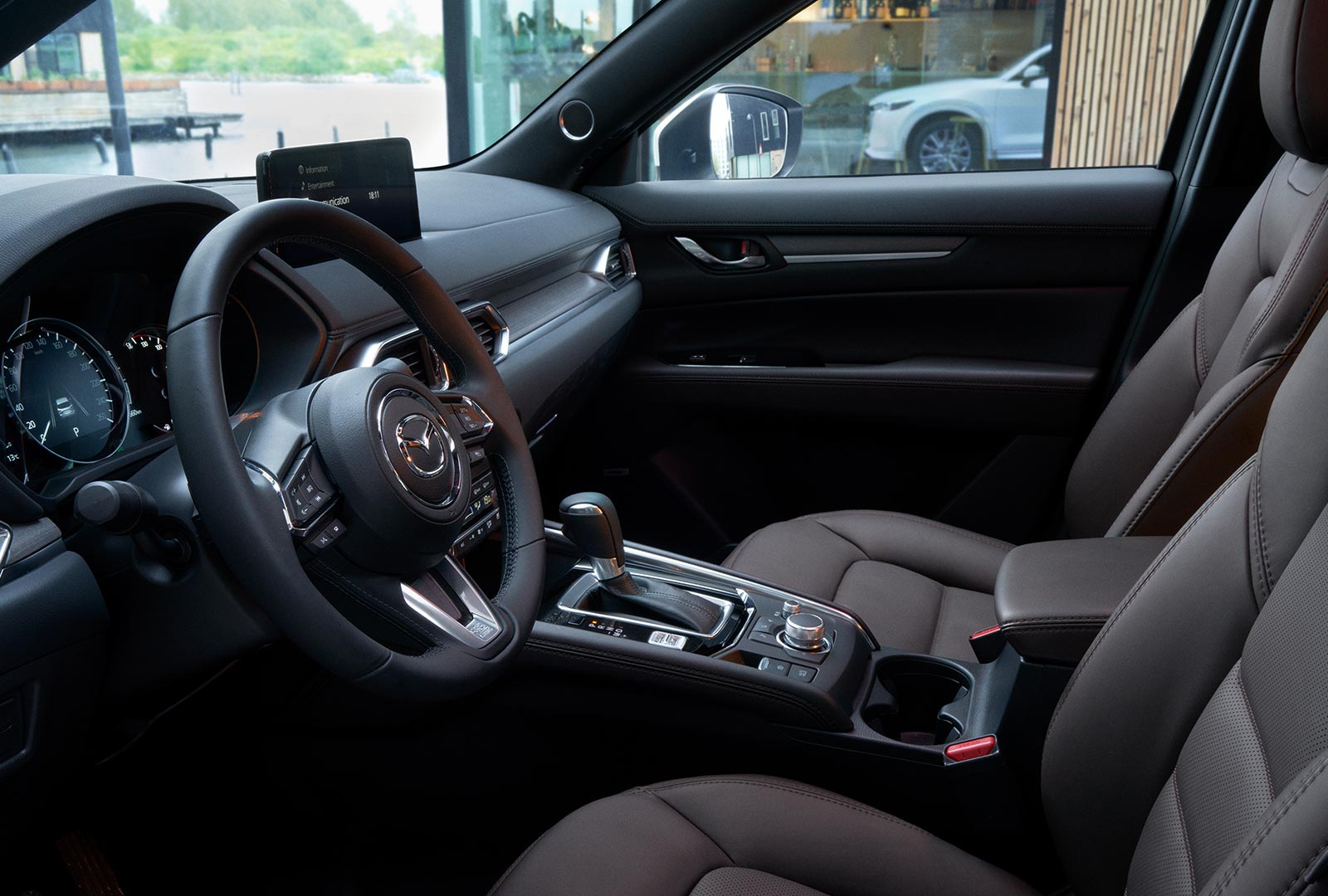 Vue de l’habitacle du CX-5 avec le volant, la console avec le bouton de commande du poste de contrôle HMI et les sièges en cuir cacao. 