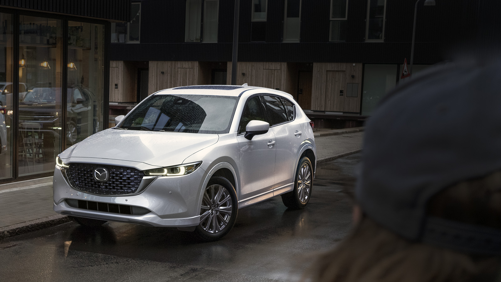 White Mazda CX-5 driving down a street. 