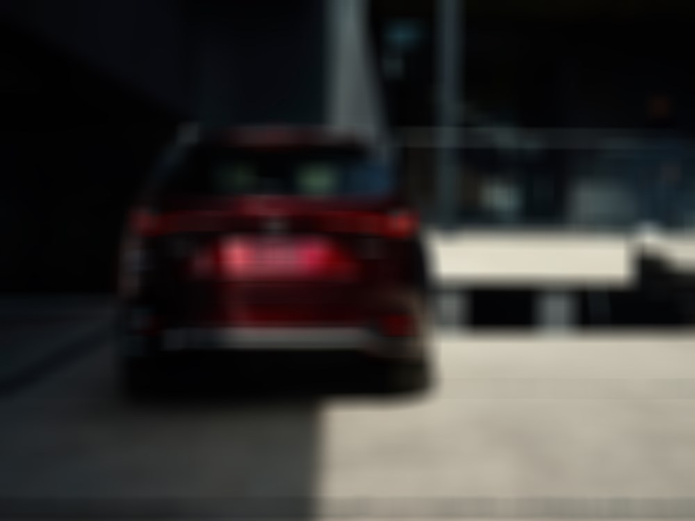 Back of the Artisan Red CX-90 parked in front of concrete building atrium with Glass railings. 