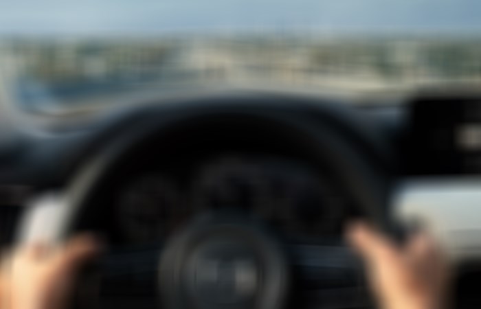 Both hands on the steering wheel, driver POV of Dash while CX-90 is in motion.