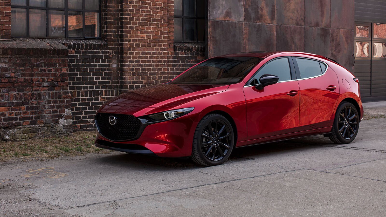 Soul Red Crystal Metallic parked on urban side street next to a worn red brick wall.  