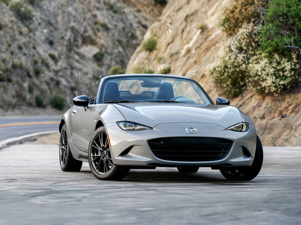 Une MX-5 ST gris aéro métallisé garée sur l’accotement d’une route escarpée.