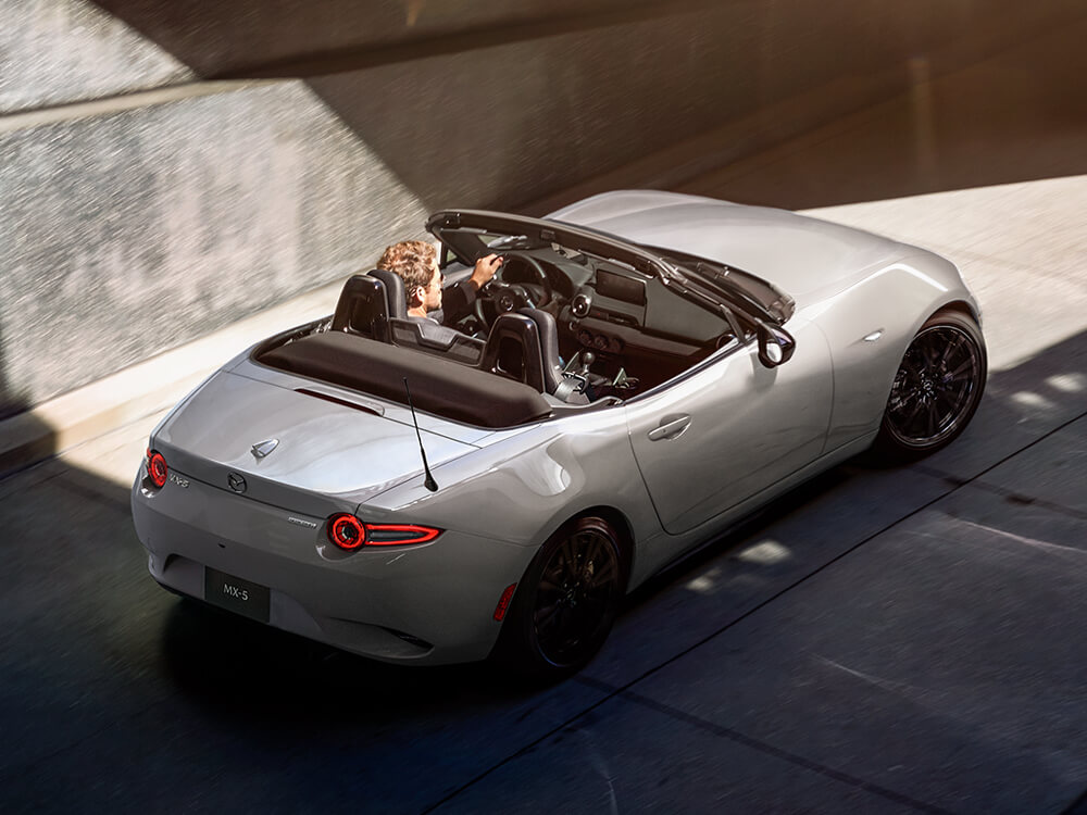 Aero Grey Metallic MX-5 drives through a beam of morning sun as it exits an underground parking lot.