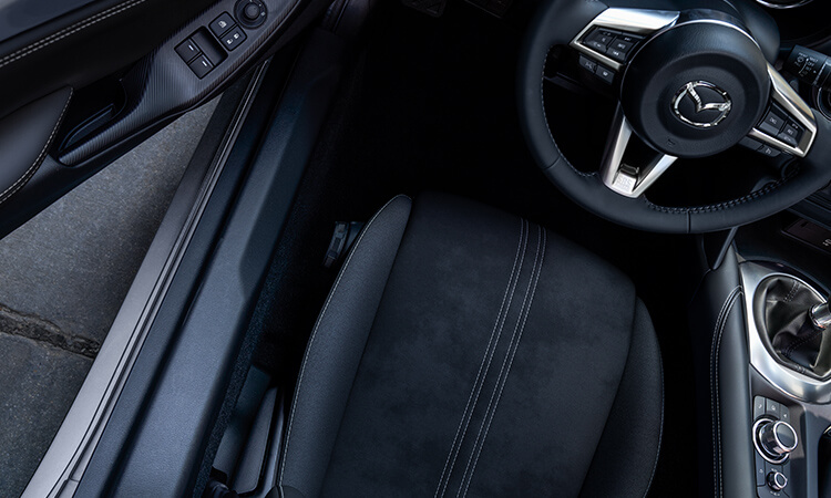 Driver’s side view of MX-5 Soft Top cockpit, looking down at the seat and steering wheel.