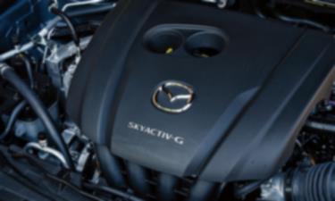 À l’intérieur du capot du CX-30, un couvercle de moteur avec le logo Mazda et l’insigne Skyactiv-G. 