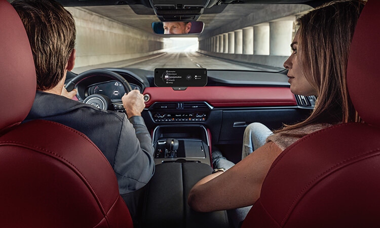 Shot inside the CX-70 shows the centre infotainment display over the shoulders of the driver and passenger inside the CX-70.